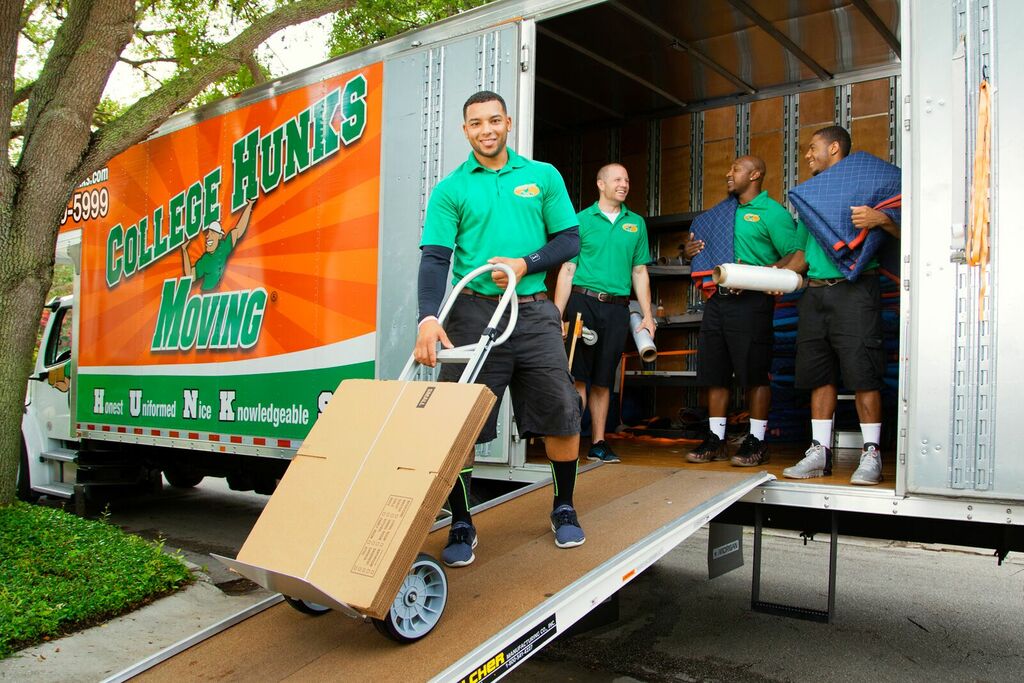 Moving company workers carrying cardboard boxes down residential street